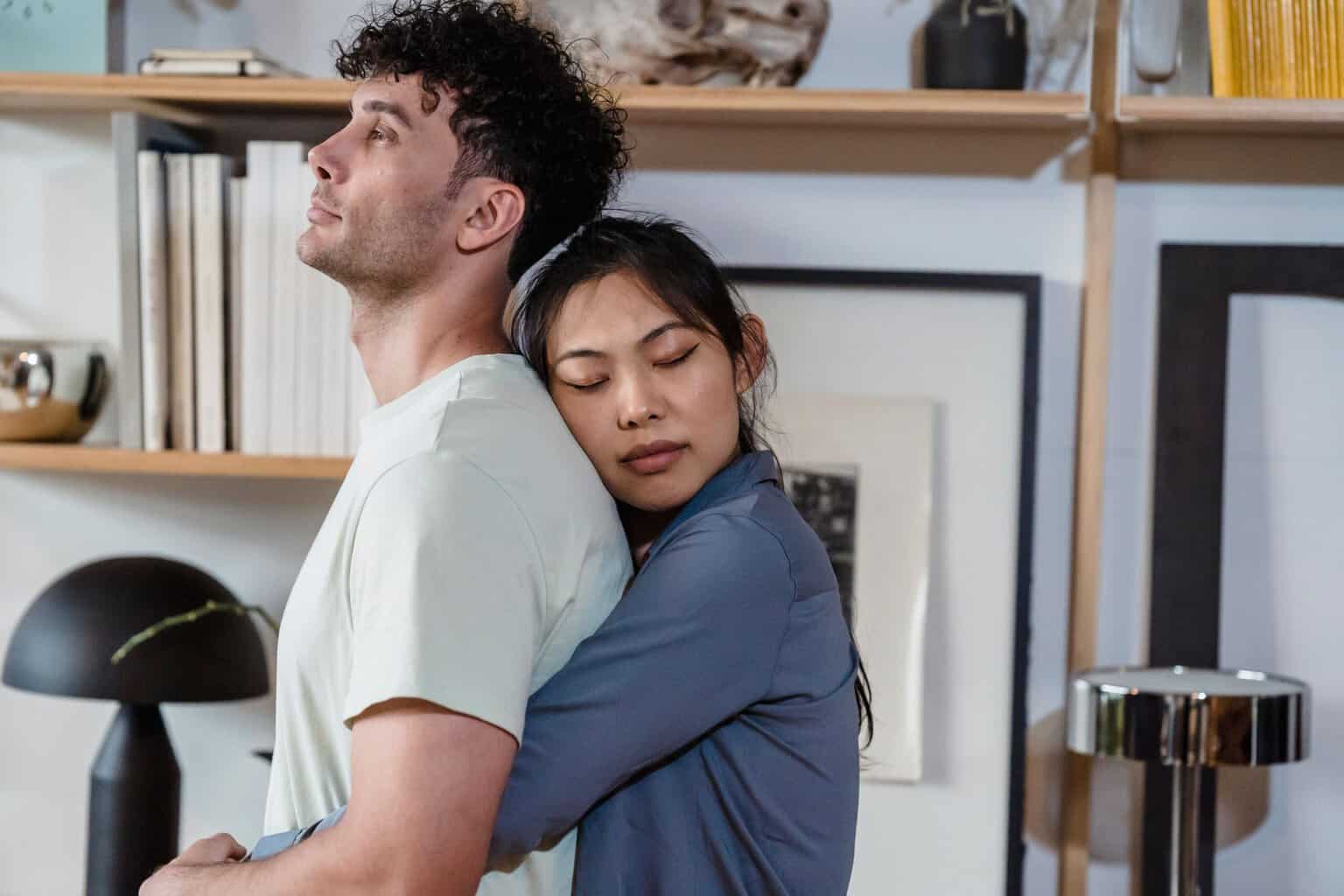 Woman hugging her partner with her eyes closed while he looks upward, representing emotional support from a loved one during addiction recovery.